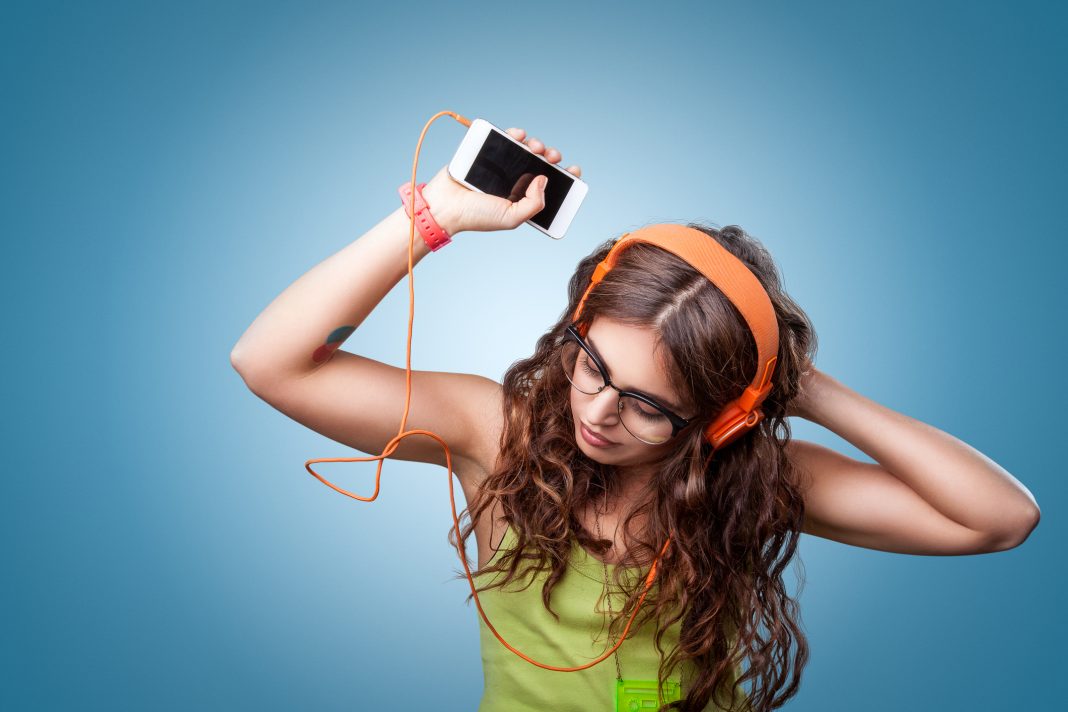 Beautiful girl in headphones listening to music and dancing
